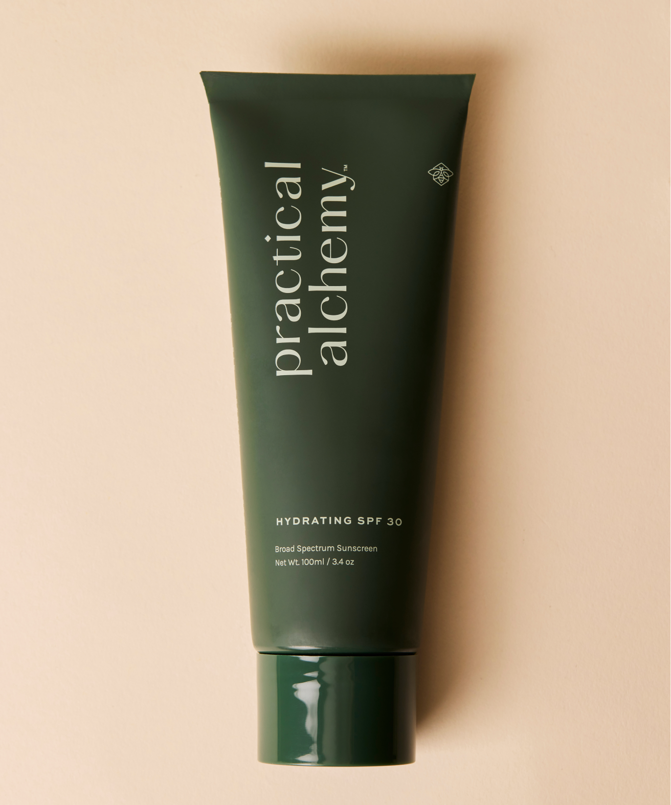 Green tube of Practical Alchemy hydrating SPF 30 sunscreen on a beige background