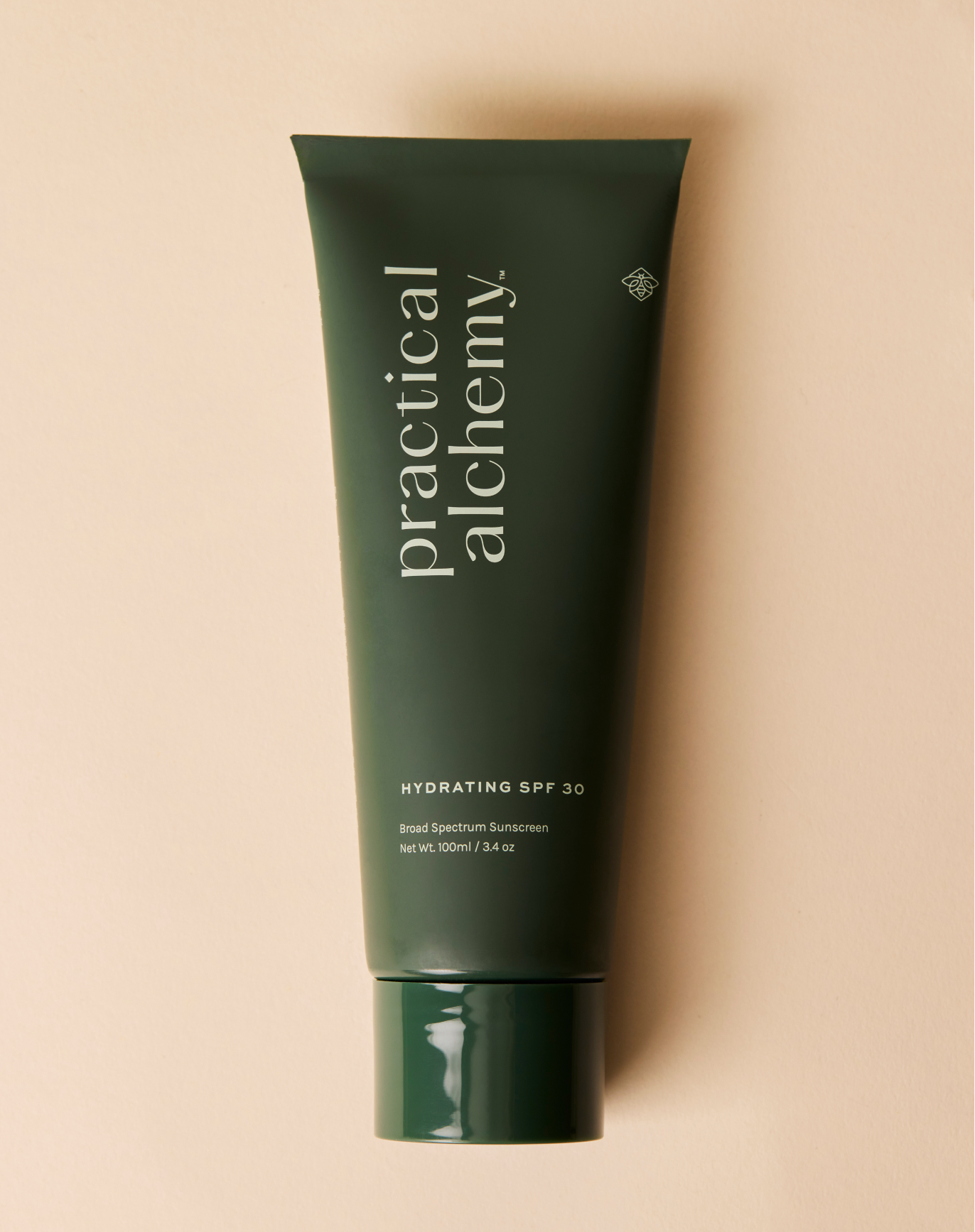 Green tube of Practical Alchemy hydrating SPF 30 sunscreen on a beige background