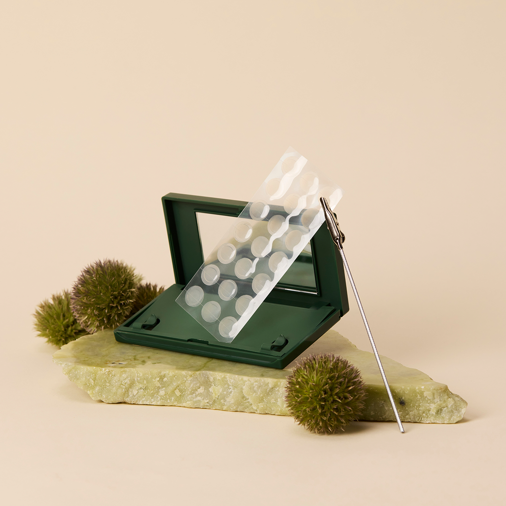 Just in Case carrying case and sheet of Vanishing Pimple Patches on a green rock and green puffs
