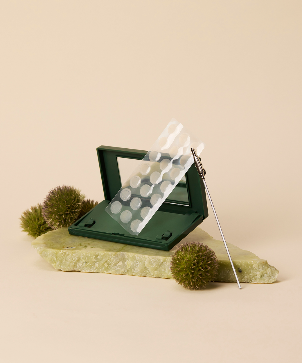Just in Case carrying case and sheet of Vanishing Pimple Patches on a green rock and green puffs