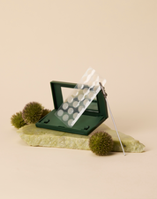 Just in Case carrying case and sheet of Vanishing Pimple Patches on a green rock and green puffs