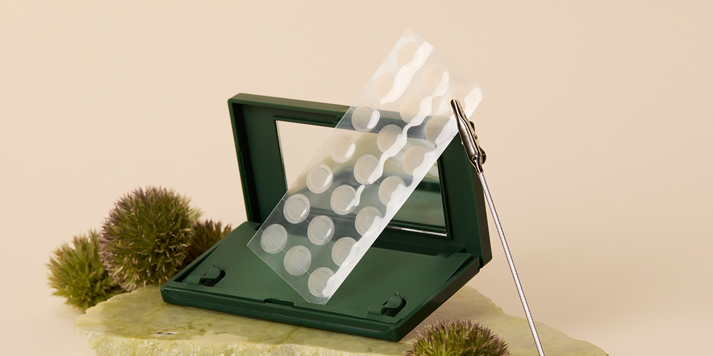 Just in Case carrying case and sheet of Vanishing Pimple Patches on a green rock and green puffs