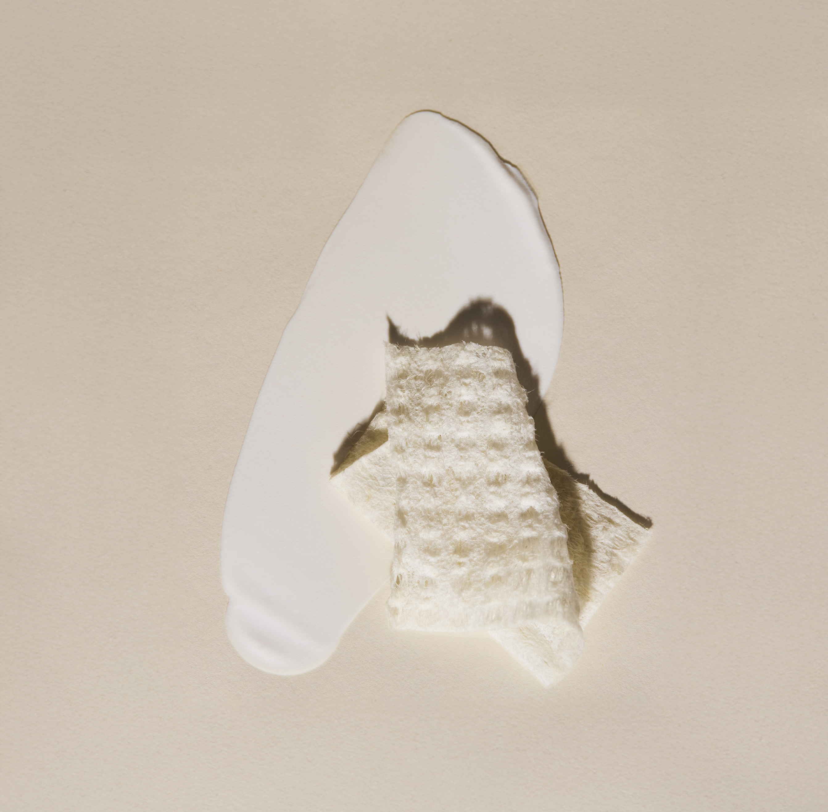 Smear of Hydrating SPF 30 sunscreen with a folding Purifying Cloth on top on a beige background