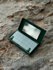 Vanishing Pimple Patches sitting in carrying case on a large slate rock