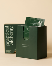 Open green box of Purify + Protect Duo sachets with lid out of focus behind on a beige background