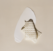 Smear of Hydrating SPF 30 sunscreen with a folding Purifying Cloth on top on a beige background